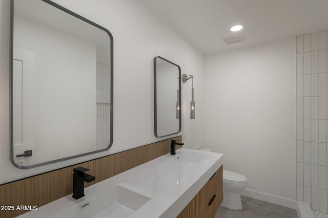 bathroom featuring tile patterned flooring, a sink, toilet, and double vanity