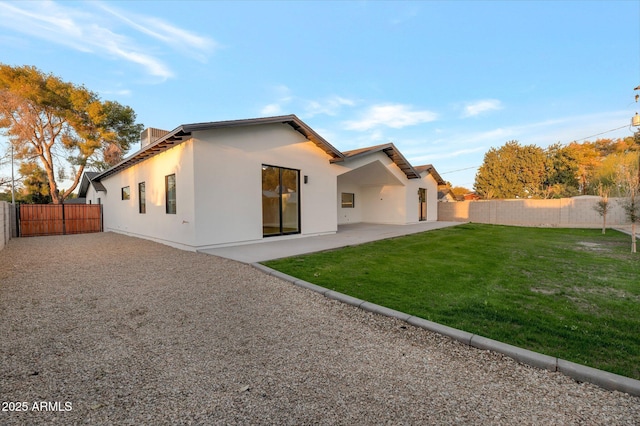 back of property featuring a yard, a patio area, a fenced backyard, and stucco siding