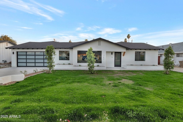 view of front facade featuring a garage, a front yard, driveway, and stucco siding