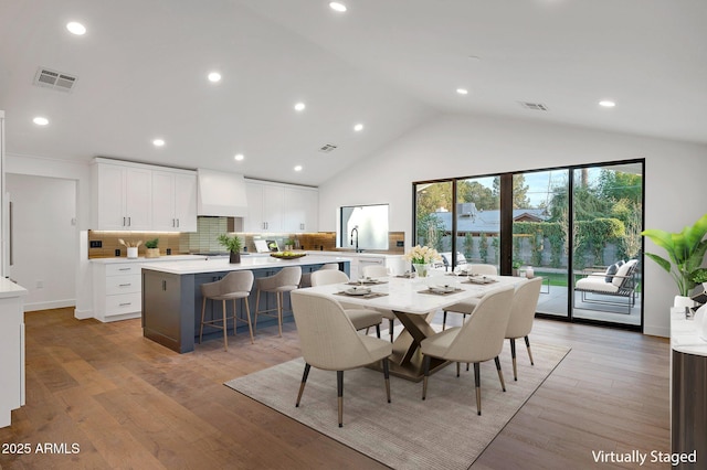 dining area with light wood-type flooring, high vaulted ceiling, visible vents, and recessed lighting