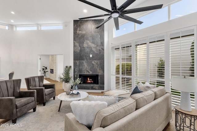 living area featuring a premium fireplace, a towering ceiling, and recessed lighting