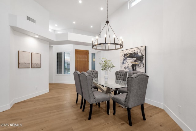 dining area with baseboards, a high ceiling, visible vents, and light wood-style floors