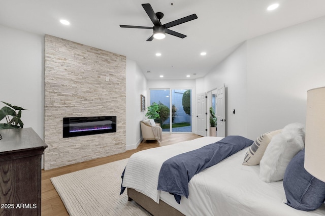 bedroom featuring recessed lighting, ceiling fan, a stone fireplace, wood finished floors, and access to outside