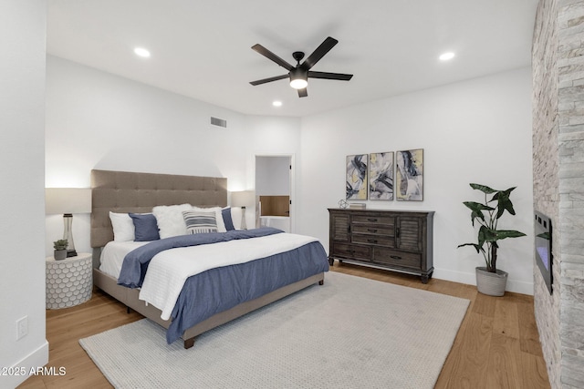 bedroom featuring recessed lighting, visible vents, a stone fireplace, and wood finished floors