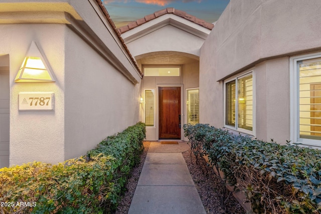 doorway to property with a tiled roof and stucco siding