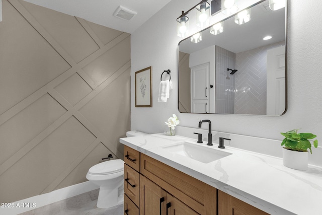 full bathroom featuring toilet, vanity, a tile shower, and visible vents