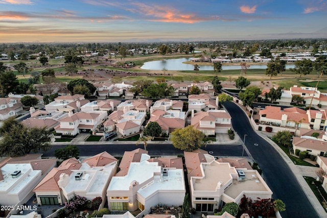 aerial view at dusk with a water view and a residential view