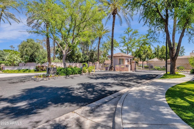 view of road featuring sidewalks, a gate, a gated entry, and curbs