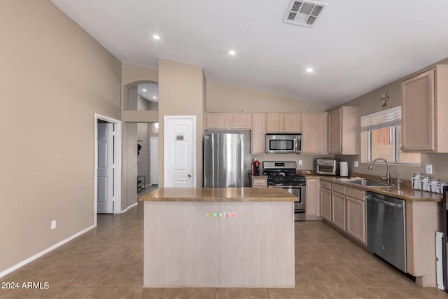 kitchen with light tile patterned flooring, sink, appliances with stainless steel finishes, and a kitchen island