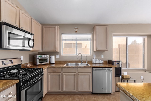 kitchen with sink, stainless steel appliances, a healthy amount of sunlight, and light tile patterned floors