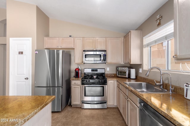 kitchen with light tile patterned flooring, light brown cabinetry, sink, appliances with stainless steel finishes, and lofted ceiling