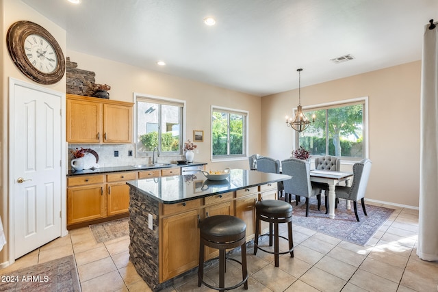 kitchen with sink, a breakfast bar, backsplash, decorative light fixtures, and a kitchen island