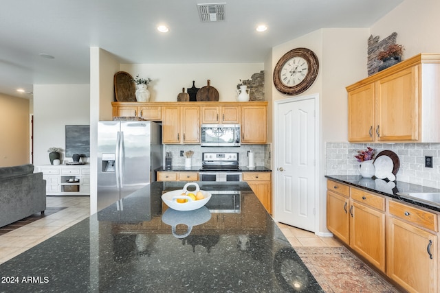 kitchen featuring light tile patterned flooring, dark stone countertops, backsplash, and appliances with stainless steel finishes