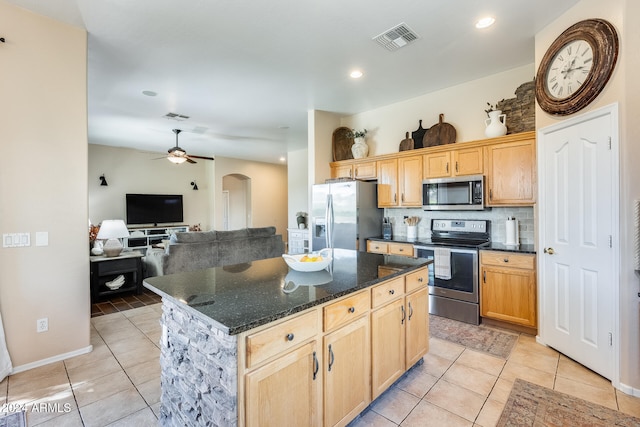 kitchen with stainless steel appliances, light tile patterned flooring, backsplash, and a kitchen island