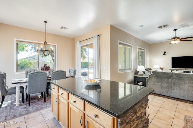 kitchen featuring dark stone counters, plenty of natural light, decorative light fixtures, and a center island