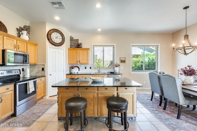 kitchen featuring dark stone countertops, a breakfast bar, appliances with stainless steel finishes, and a center island