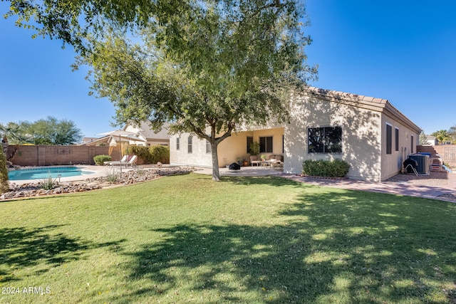 back of house featuring a lawn, a fenced in pool, and a patio area