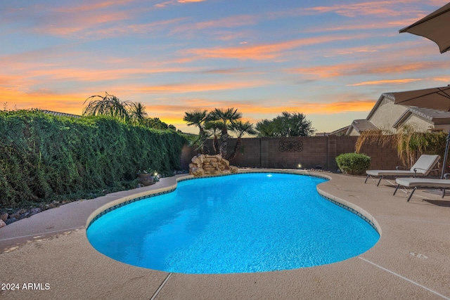 pool at dusk featuring a patio area