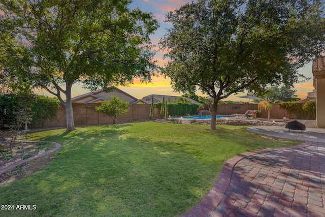 yard at dusk with a fenced in pool and a patio area