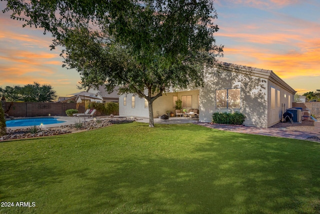 back house at dusk with a patio, a fenced in pool, and a yard