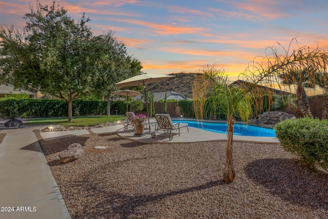 pool at dusk featuring a patio area