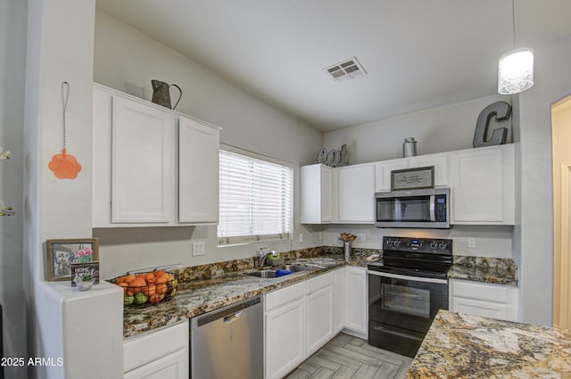 kitchen featuring appliances with stainless steel finishes, sink, dark stone countertops, and white cabinets