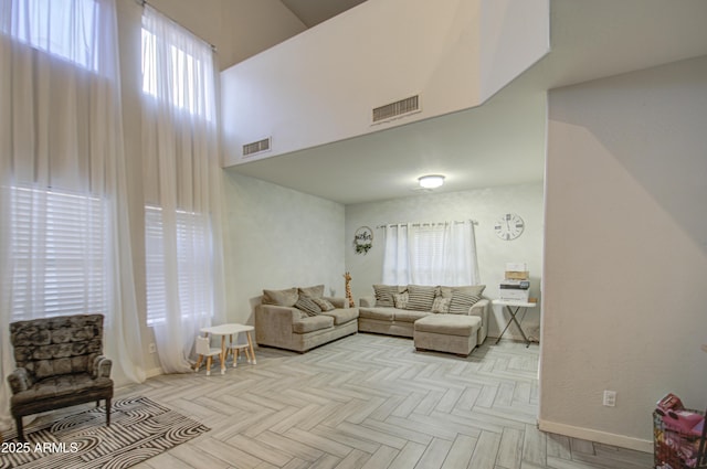 living room featuring a towering ceiling, plenty of natural light, and light parquet floors