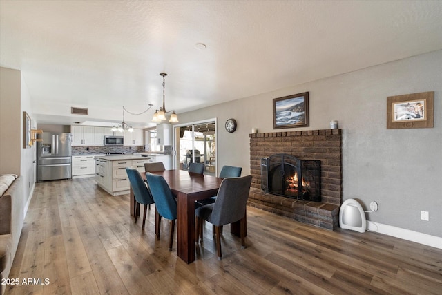 11621 N 39th Dr, Phoenix, AZ 85029 - dining room with visible vents, light wood-style flooring, a notable chandelier, and a fireplace