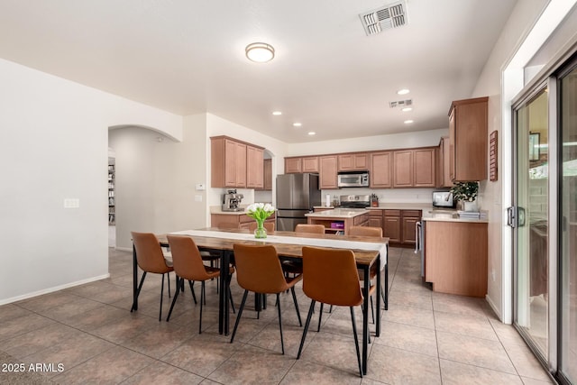 kitchen featuring a kitchen breakfast bar, light tile patterned floors, stainless steel appliances, and a center island