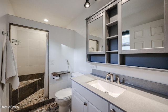 bathroom featuring vanity, toilet, and tiled shower