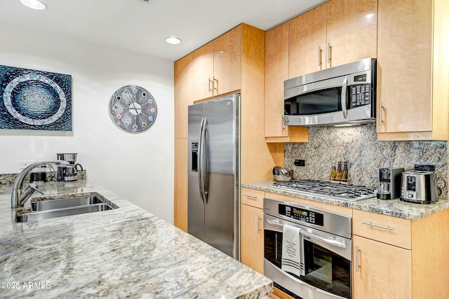 kitchen with recessed lighting, stainless steel appliances, a sink, light stone countertops, and tasteful backsplash