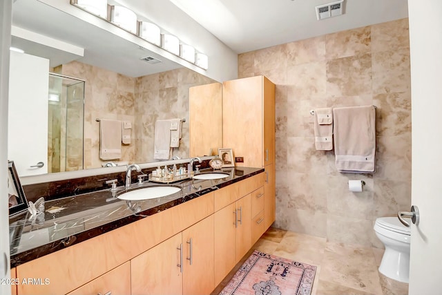 full bath with visible vents, a sink, and tile walls