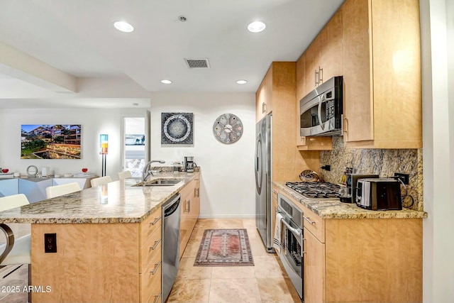 kitchen featuring visible vents, decorative backsplash, a peninsula, stainless steel appliances, and a sink