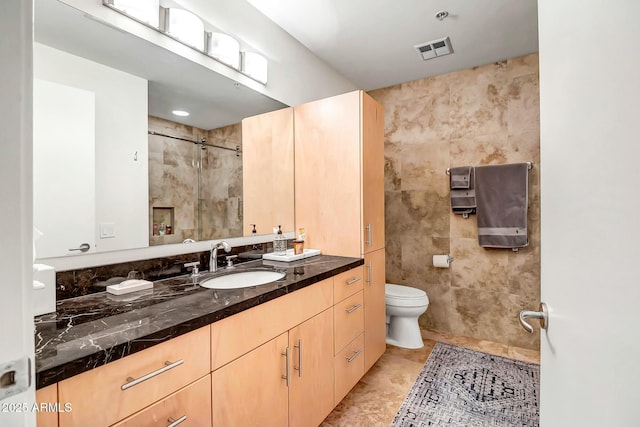 full bathroom featuring toilet, vanity, visible vents, tile walls, and tile patterned floors