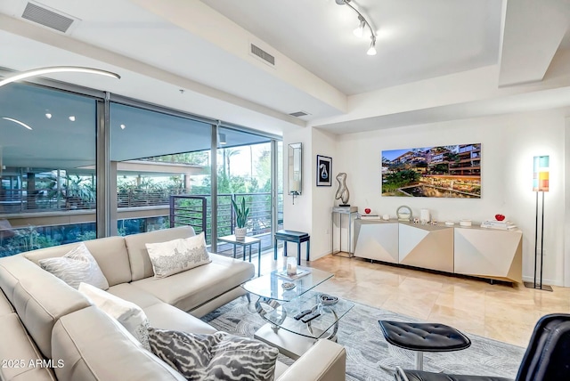 living room with light tile patterned floors, rail lighting, visible vents, and baseboards