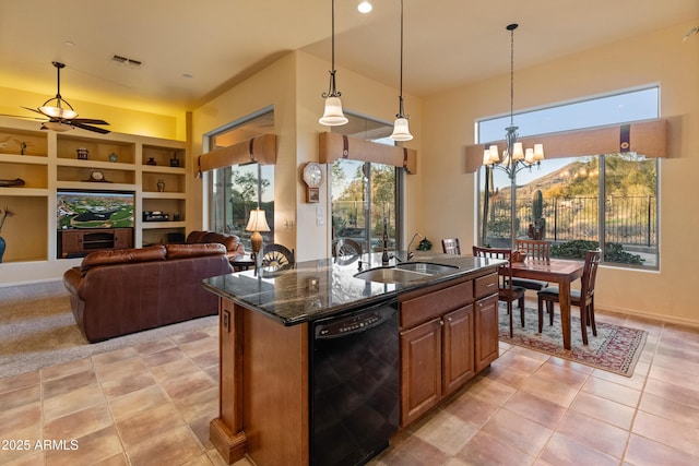 kitchen with decorative light fixtures, dishwasher, sink, dark stone countertops, and a center island with sink