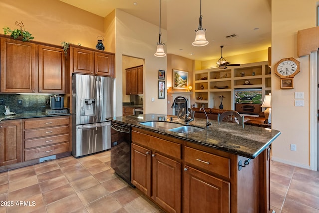 kitchen with dishwasher, sink, hanging light fixtures, stainless steel fridge with ice dispenser, and a center island with sink