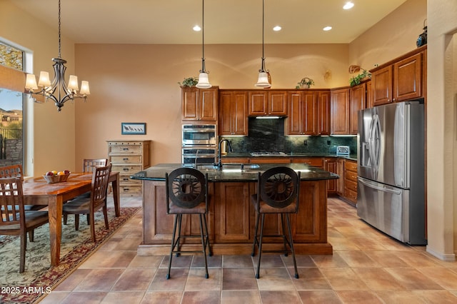 kitchen featuring pendant lighting, sink, appliances with stainless steel finishes, tasteful backsplash, and an island with sink