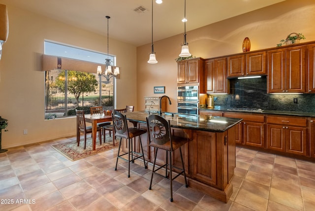 kitchen featuring stainless steel appliances, a kitchen island with sink, a kitchen bar, and decorative backsplash