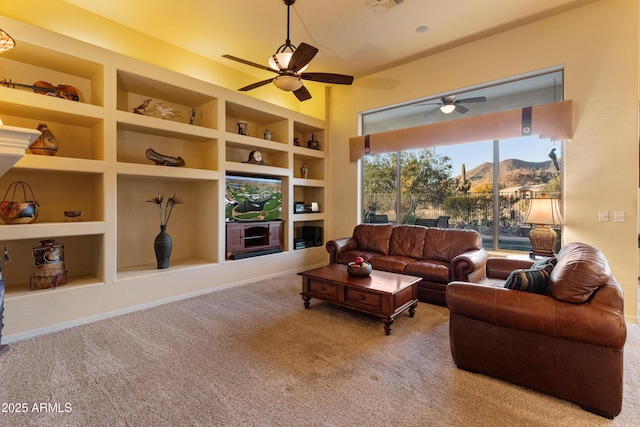 living room with ceiling fan, a fireplace, carpet floors, and built in features