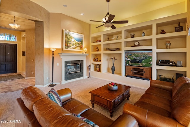 living room featuring built in shelves, a fireplace, light colored carpet, and ceiling fan