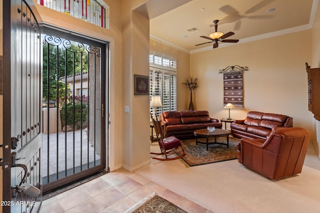 tiled foyer featuring crown molding and ceiling fan