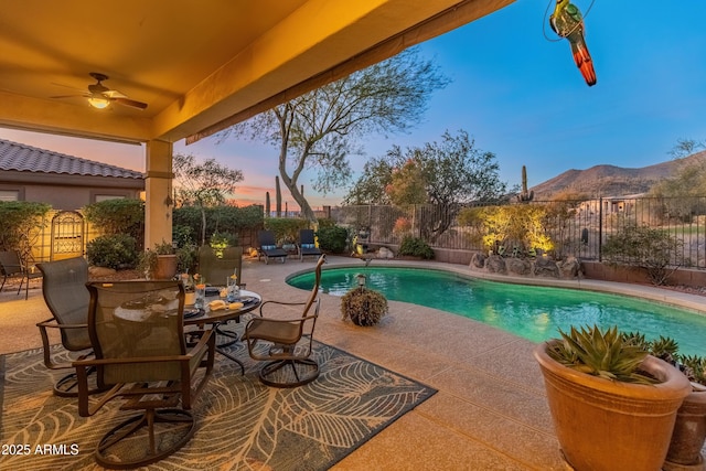 pool at dusk with a patio and ceiling fan