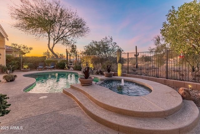 pool at dusk with pool water feature and a patio