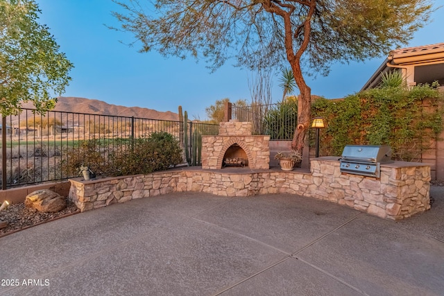 view of patio / terrace with a mountain view, area for grilling, and an outdoor stone fireplace