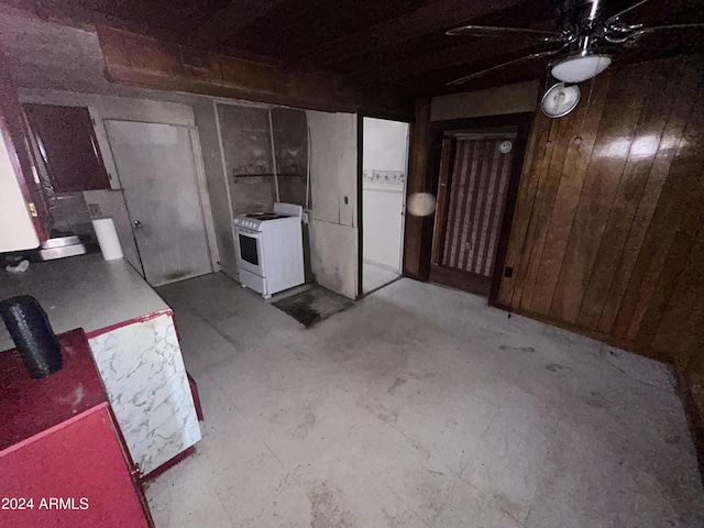 basement with ceiling fan and wooden walls