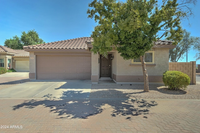 view of front of property featuring concrete driveway, an attached garage, a tile roof, and stucco siding