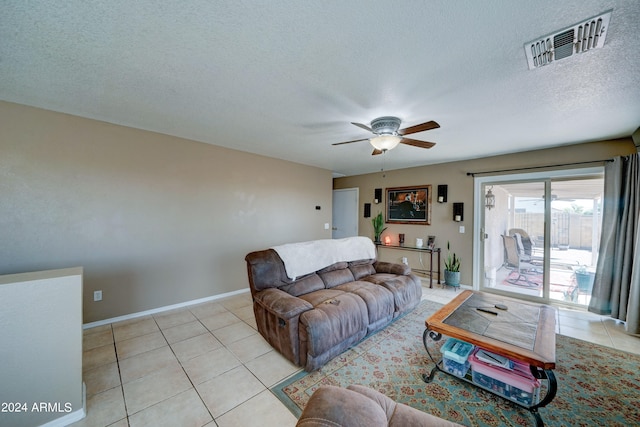 living room with light tile patterned floors, a textured ceiling, a ceiling fan, visible vents, and baseboards