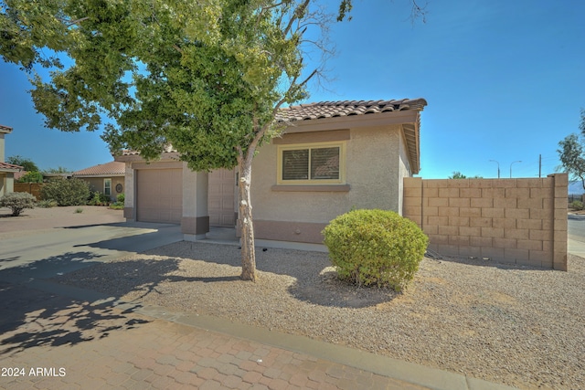 mediterranean / spanish house with a garage, concrete driveway, a tile roof, and stucco siding