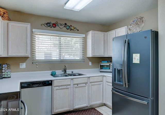 kitchen with white cabinetry, sink, a textured ceiling, light tile patterned flooring, and appliances with stainless steel finishes